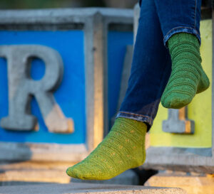 Person wearing jeans and lacy green socks.